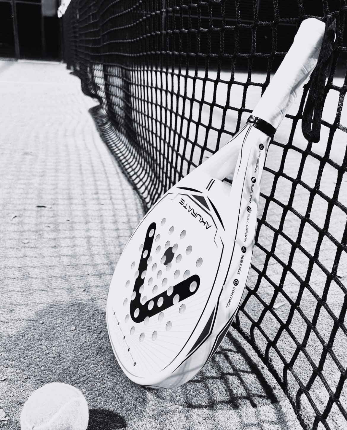 Raquette Aku-Control sur un terrain de padel (noir et blanc)